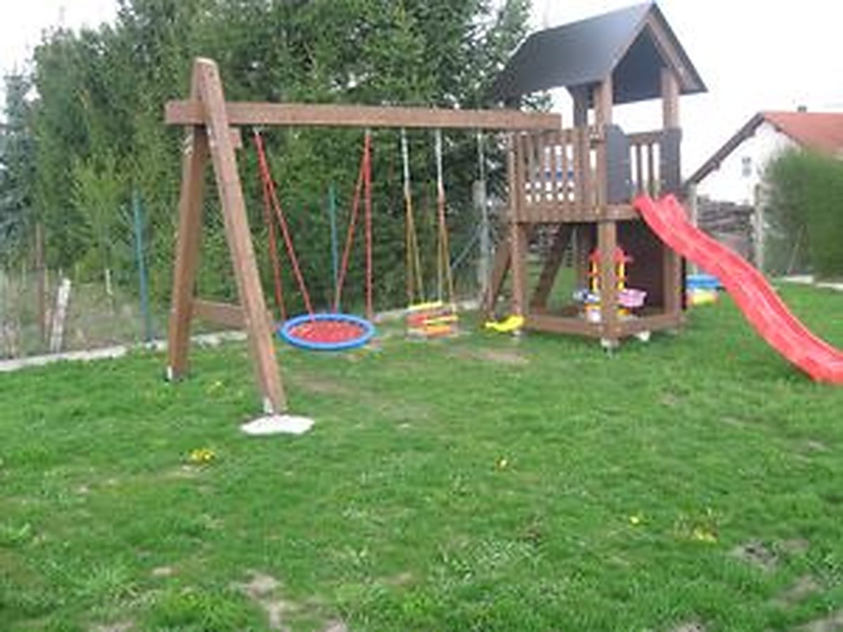 Herní sestava s houpačkami a skluzavkou na zahradě